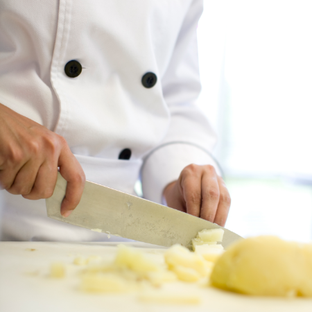 Kock i vit rock hackar potatis